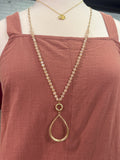 Gold chain necklace on a mannequin with a brown garment