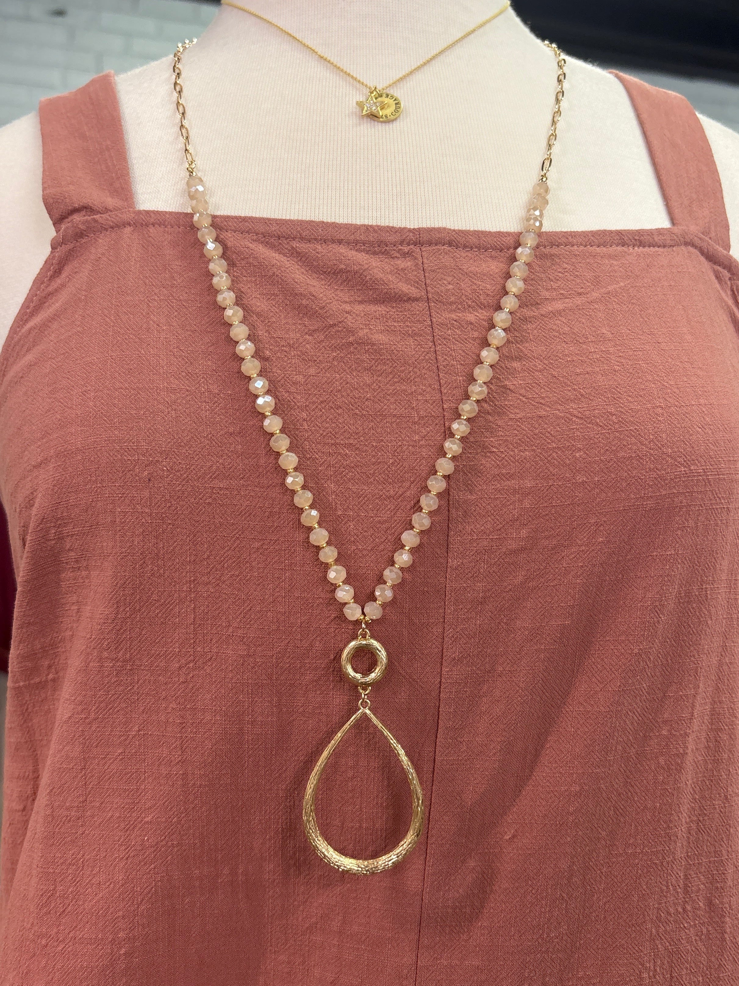 Gold chain necklace on a mannequin with a brown garment